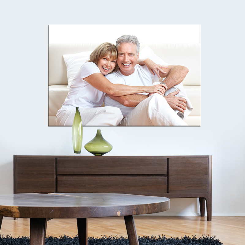 Fotoobraz ze zdjęcia przedstawiający uśmiechniętą parę w salonie, obraz zawieszony nad komodą